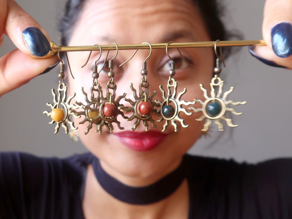 Sheila of Satin Crystals behind a stick hanging with yellow jasper, red jasper and bloodstone sun earrings