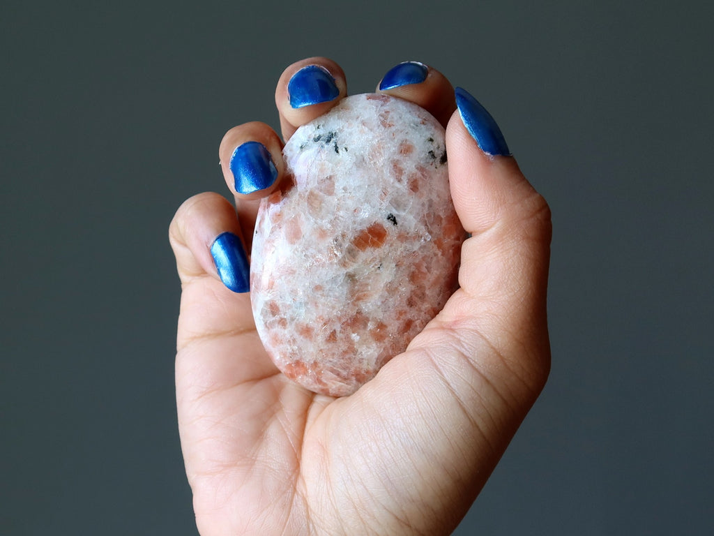 hand holding sunstone palm stone