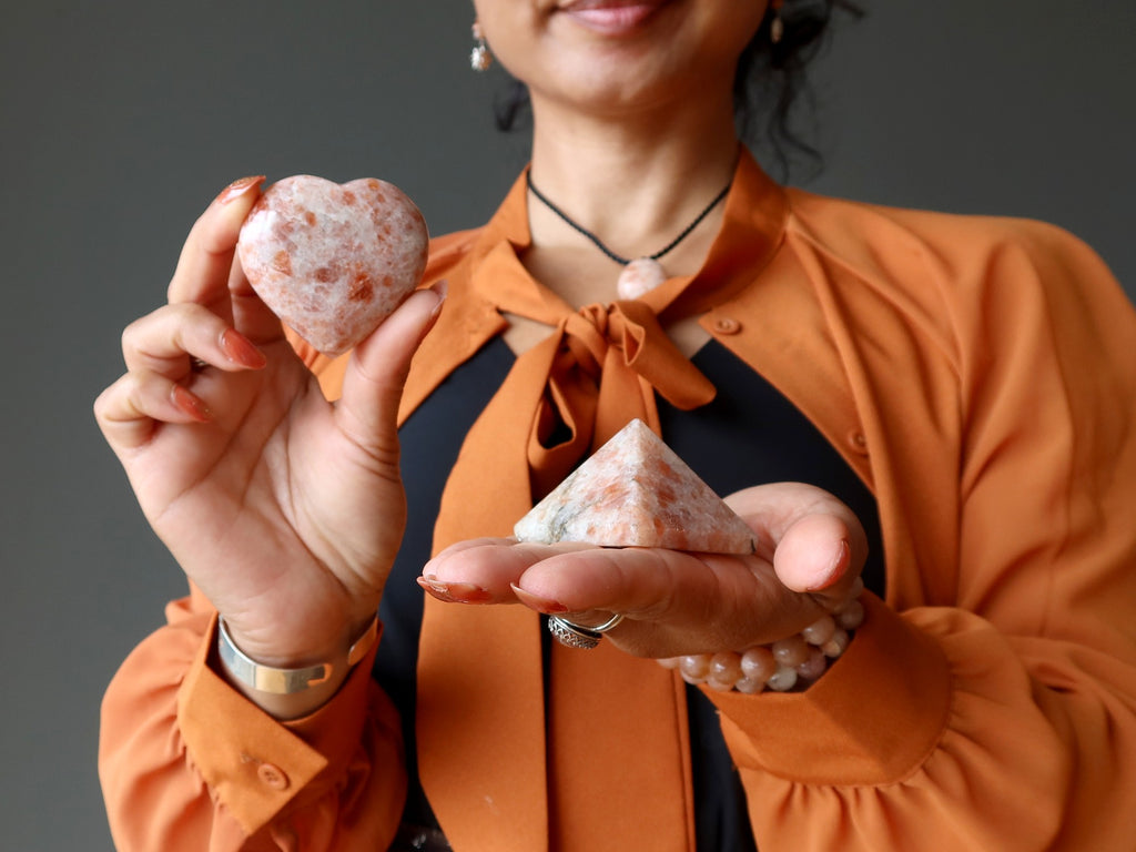 woman holding sunstone pyramid and heart