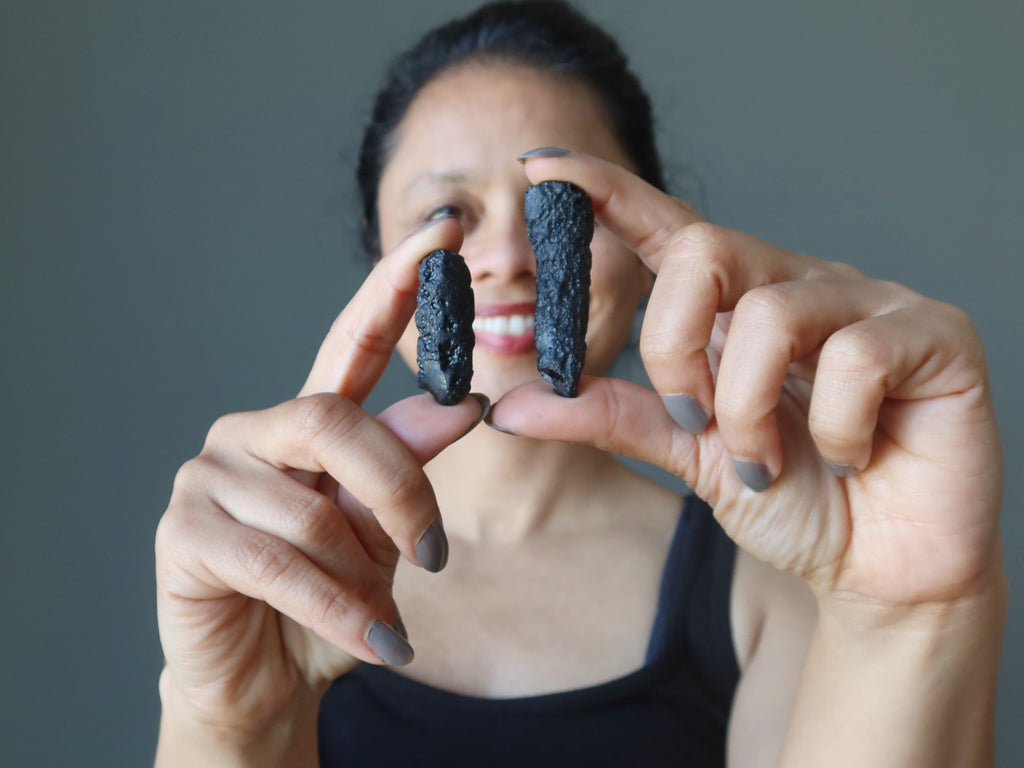 woman holding two black tektite stones