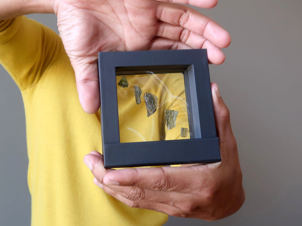 5 green moldavite meteorites in a display case