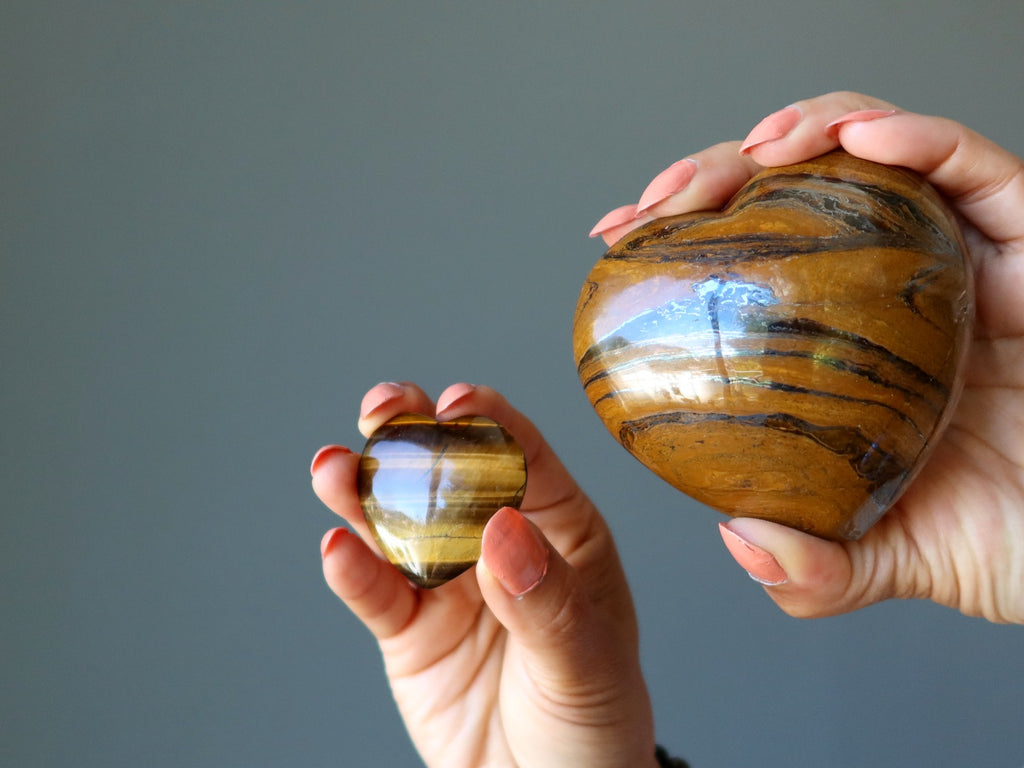 hands holding two tigers eye hearts