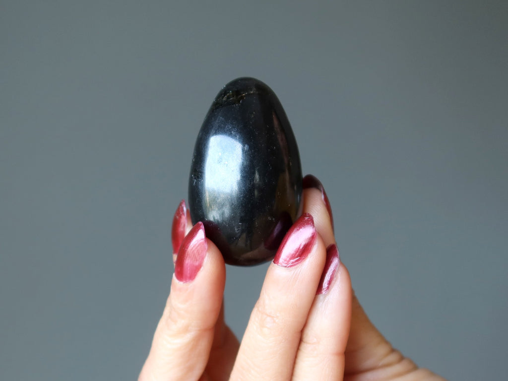 hand holding up a black tourmaline egg