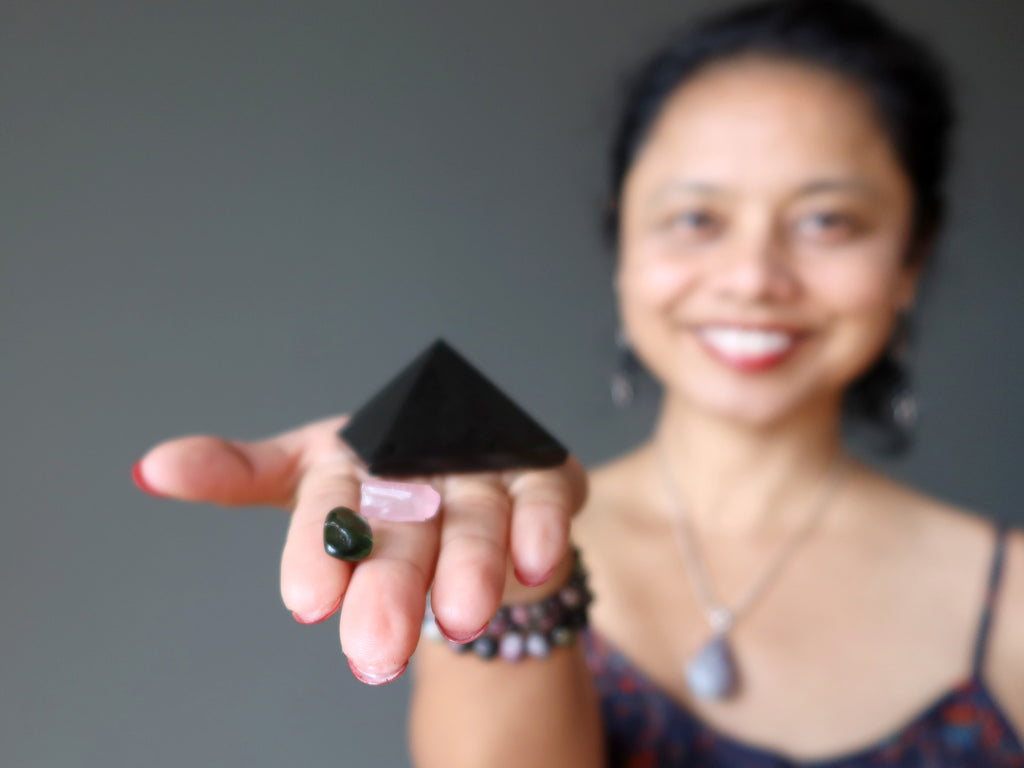 sheila of satin crystals holding black tourmaline pyramid, pink pyramid raw and tumbled moldavite