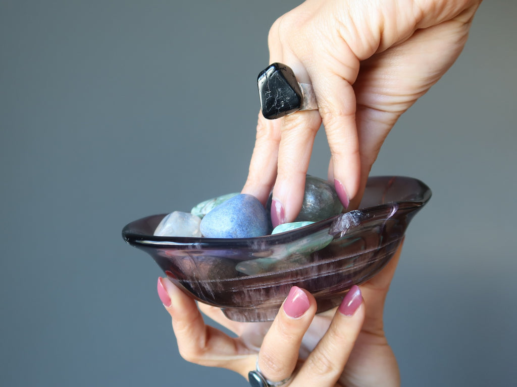 hand in a bowl full of tumbled stones