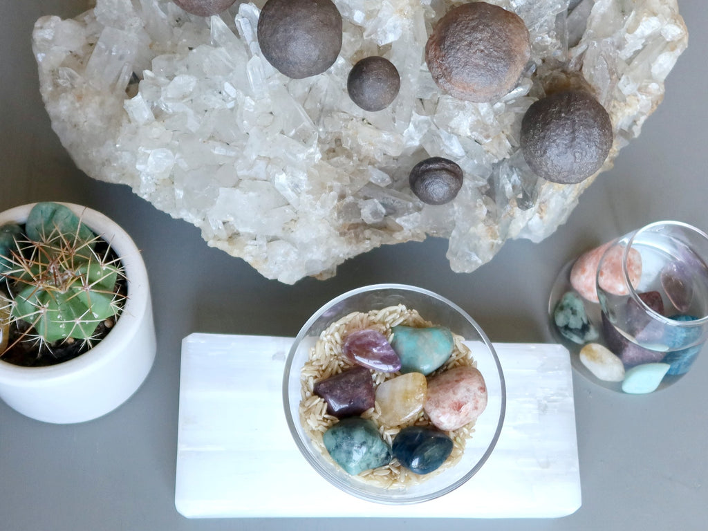 tumbled stones and moqui balls on quartz cluster, selenite slab, in water, in a cactus pot and on brown rice