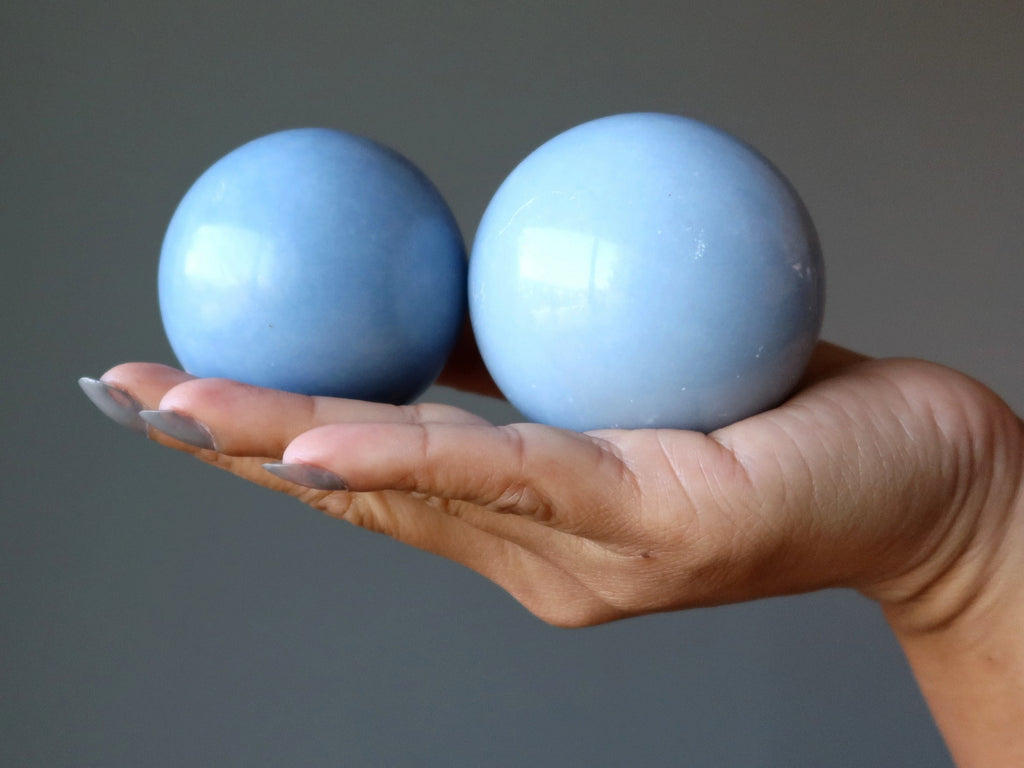 hand holding two angelite spheres