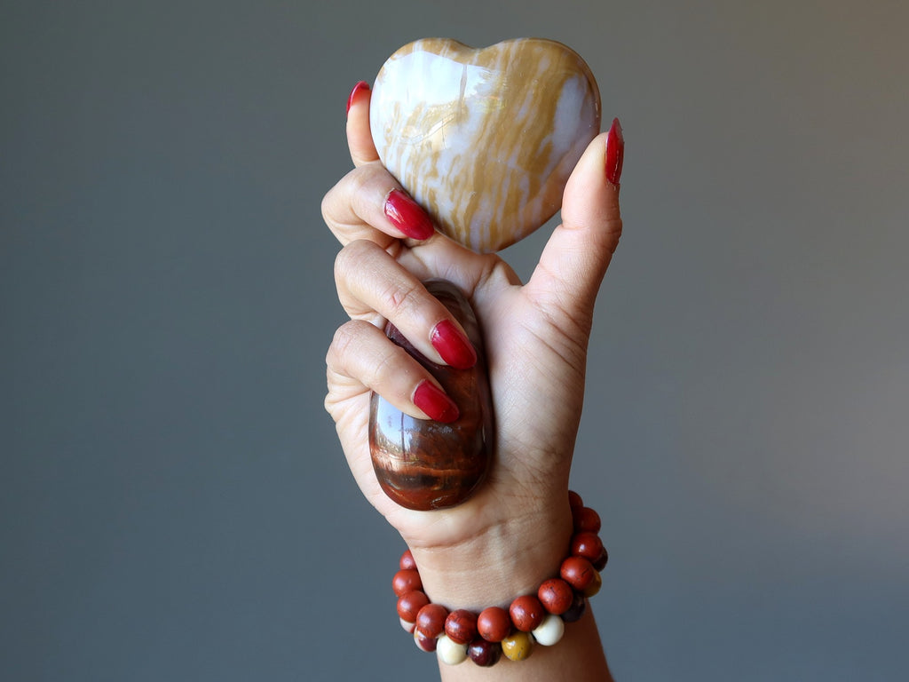 hand holding jasper heart, massage wand and wearing jasper stretch bracelets