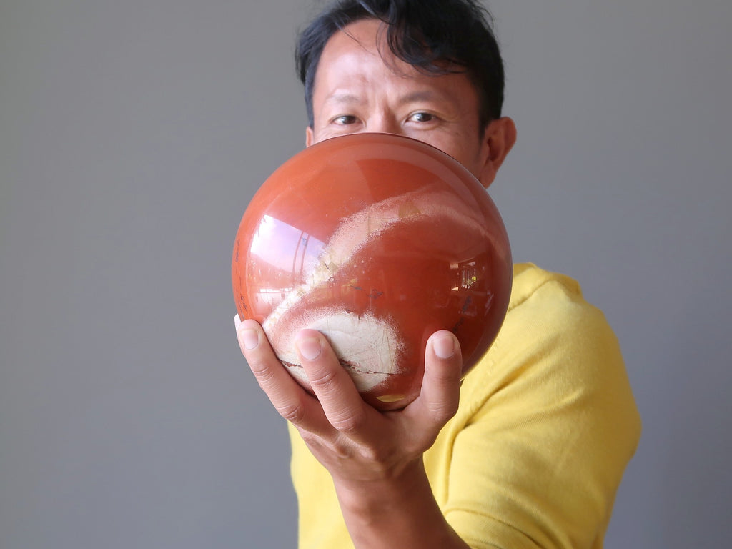 man holding a large red jasper sphere