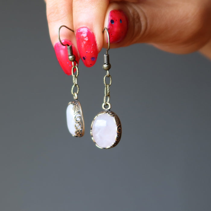 hands holding a pair of rose quartz earrings