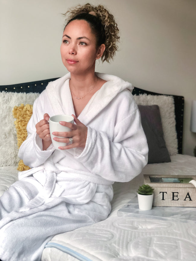 Girl in robe looking out the window with tea