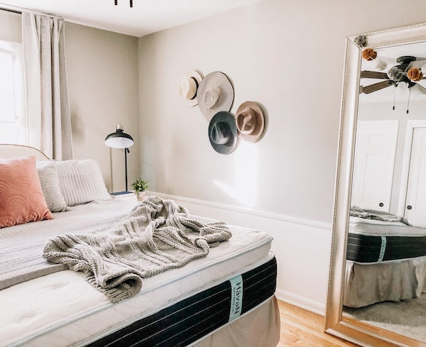 Bedroom styled with hats on walls and colours pillows and a fuzzy blanket