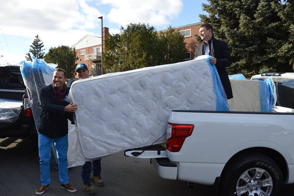 Three Haven Mattress staff loading bed-in-box mattresses into back of truck for donation to those in need