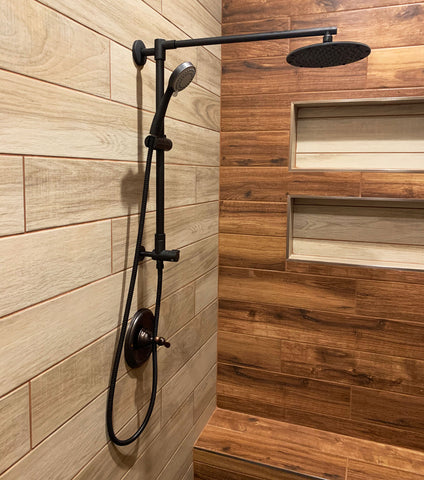 Oil-rubbed bronze rain shower system in a warm and cosy feeling bathroom. Polaris 1 rain shower system in oil-rubbed bronze goes together with warm brown wooden walls.