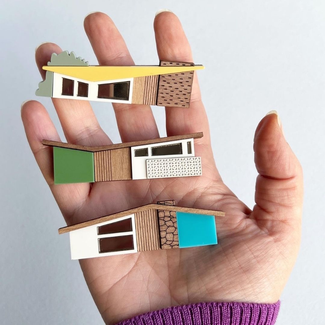 Three colourful house brooches held in the palm of a hand