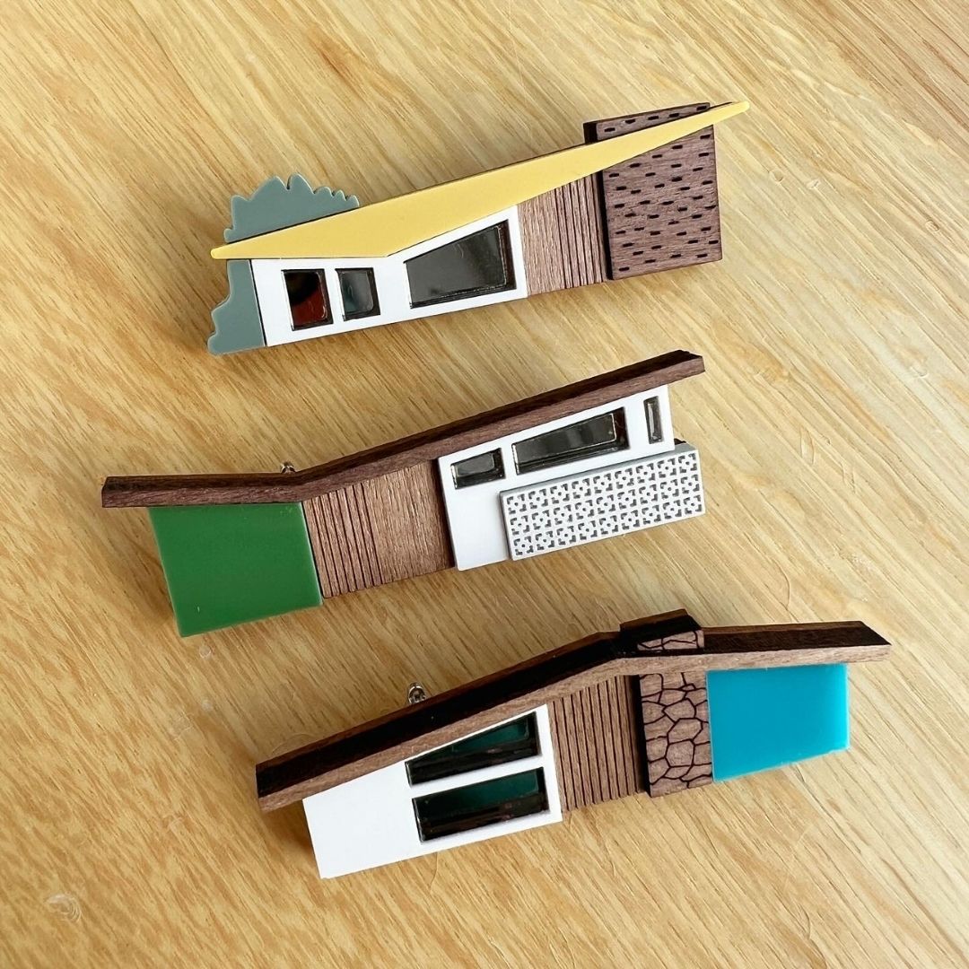 three midcentury house brooches on a wooden background