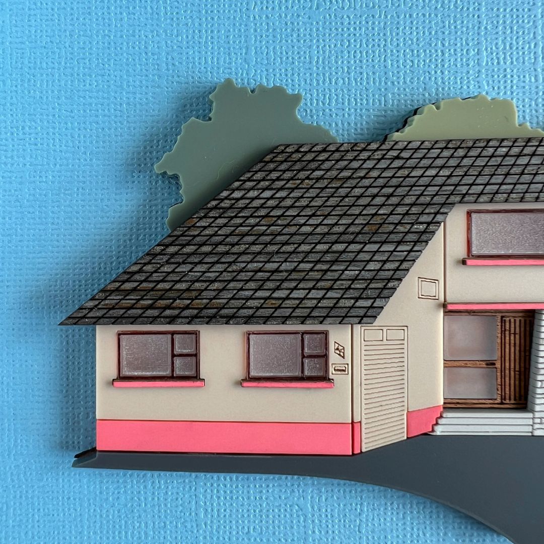 Close up on a miniature house artwork, showing the windows and roof detail
