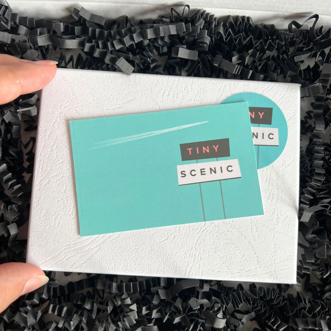 A white gift box with branded Tiny Scenic sticker and Tiny Scenic business card