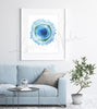Framed watercolor painting of a B cell. The painting is hanging over a blue couch.