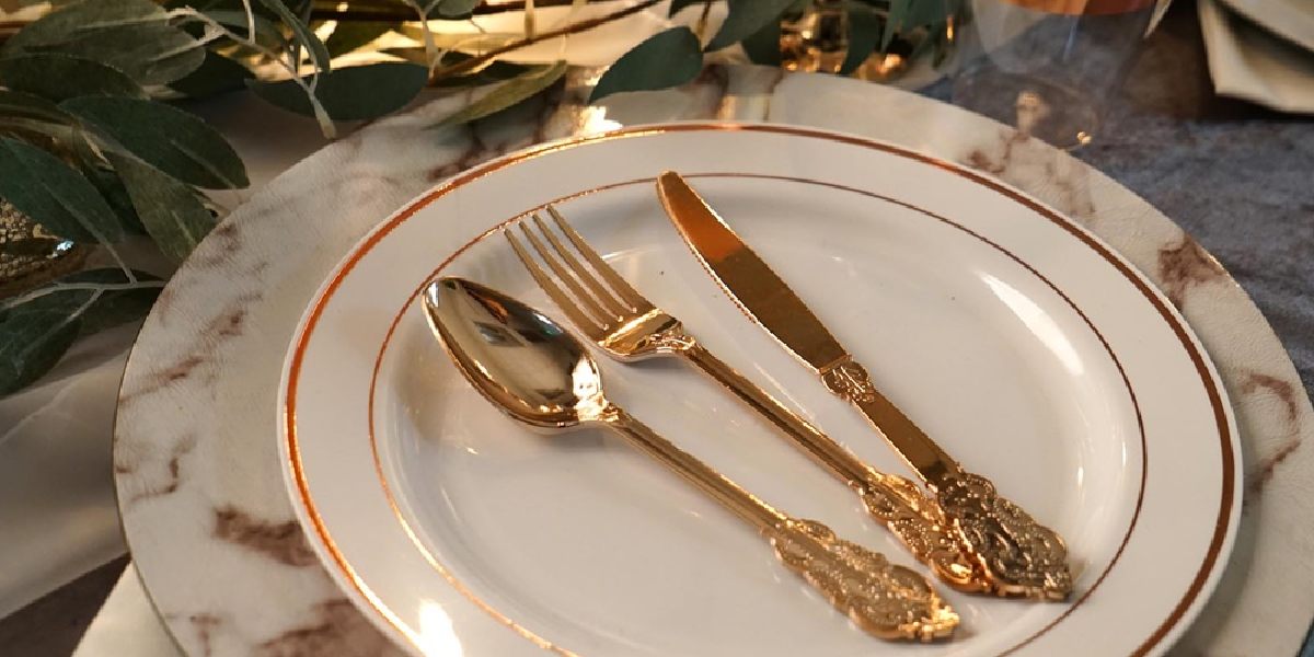 Table setting with chargers: White plates, gold cutlery