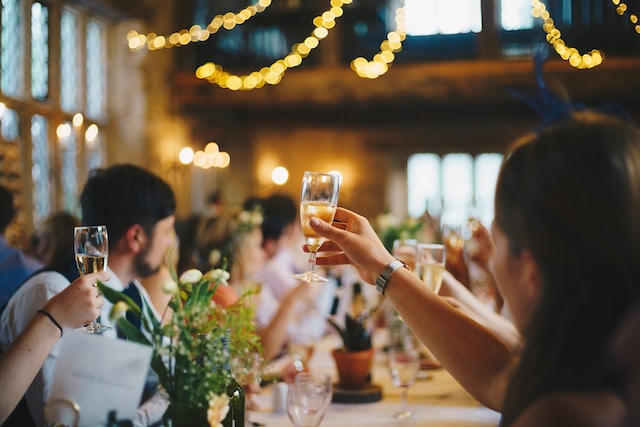 People raising their wine glasses with hanging string lights