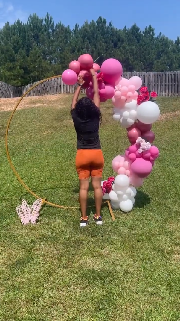 Person adding flowers to the balloon garland