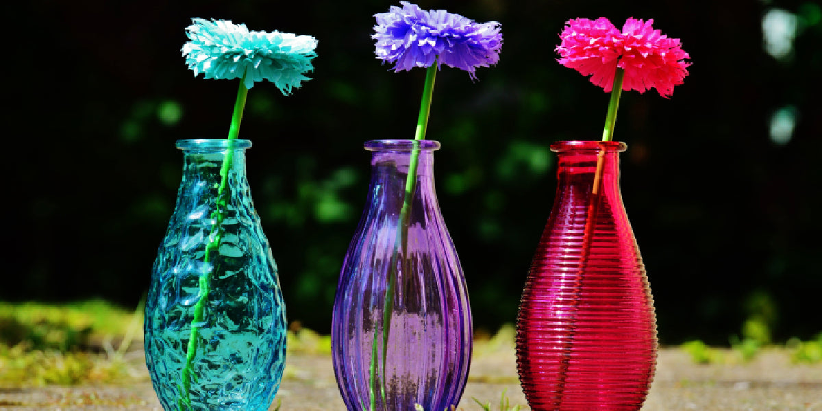Colorful DIY centerpiece ideas: Three matching vases with single, bright flowers. Turquoise, purple, and red