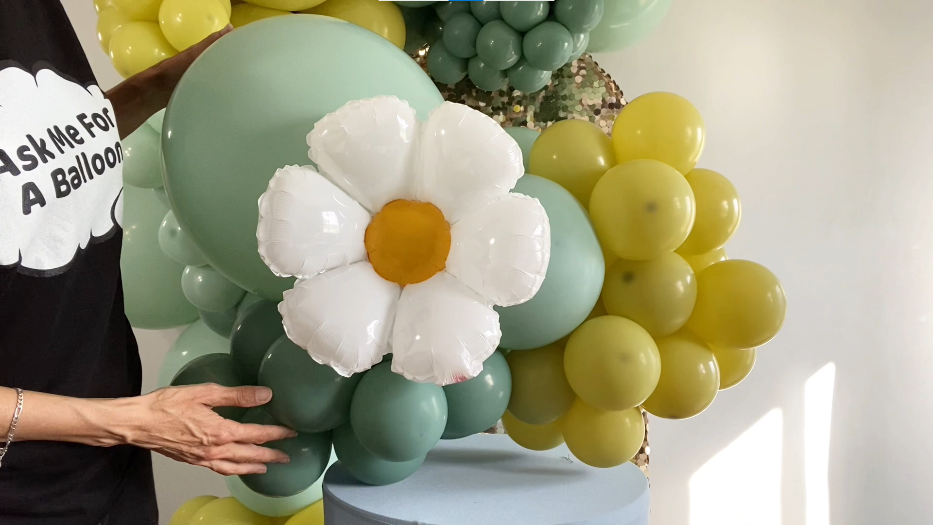 A daisy balloon with green and gold balloons on the background