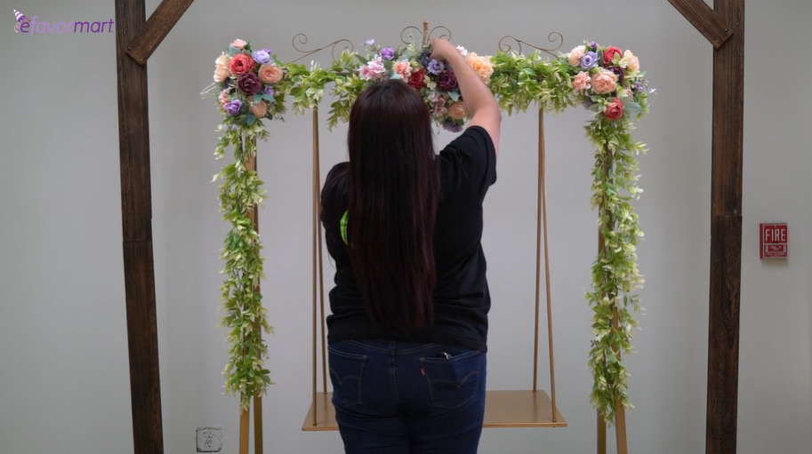 Woman adding floral decorations to a swinging metal cake stand