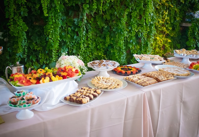 Buffet decor with table linens, dish bowls, trays, and greenery backdrop