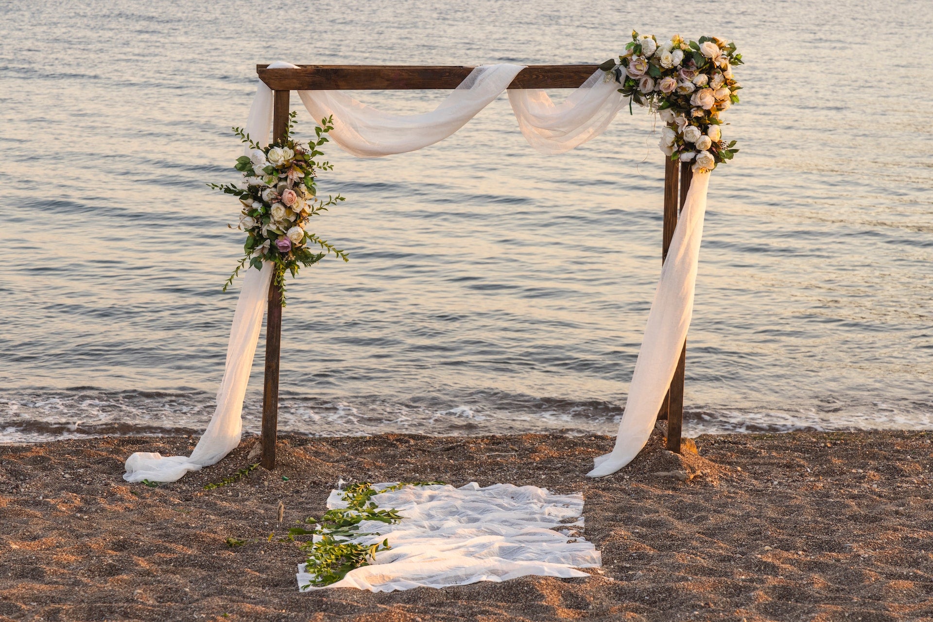 Beach wedding arch designed with fabric and flowers