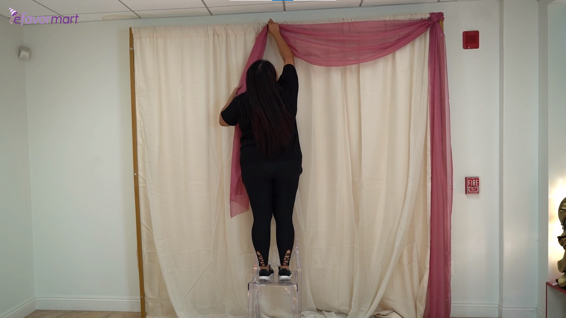 Person assembling a backdrop stand with curtain drapes