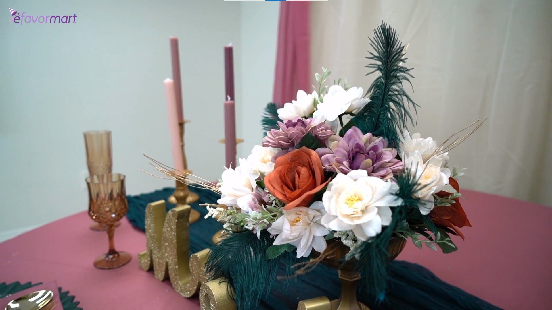 A vase with mixed artificial flowers and taper candles in metal candle holders