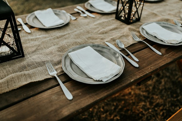 Rustic wedding tablescape with burlap runner and metal lanterns.