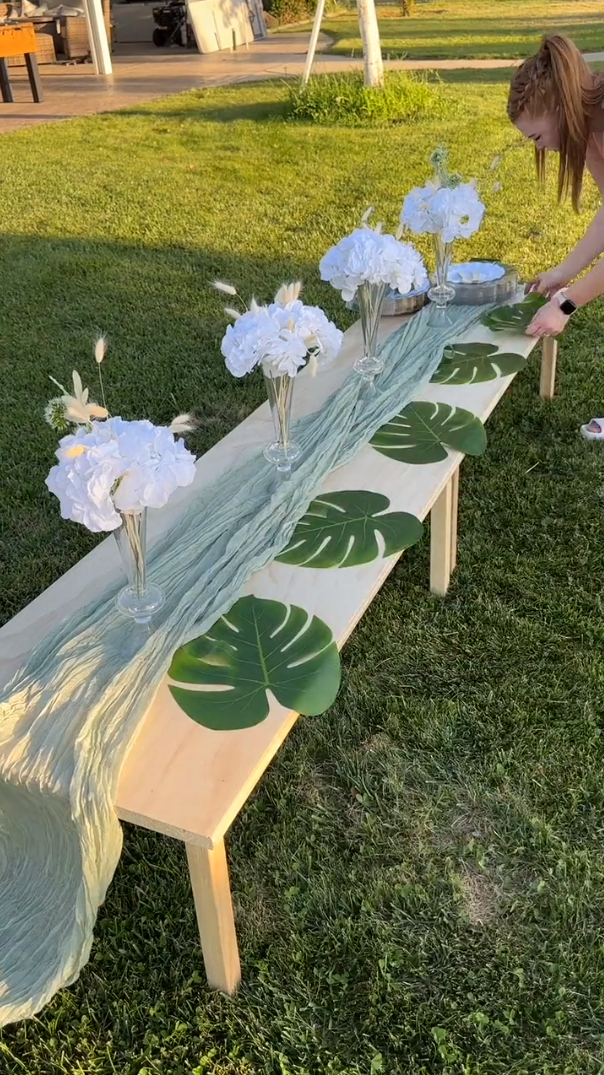 Picnic table designed with runner, glass vases, flowers, and greenery