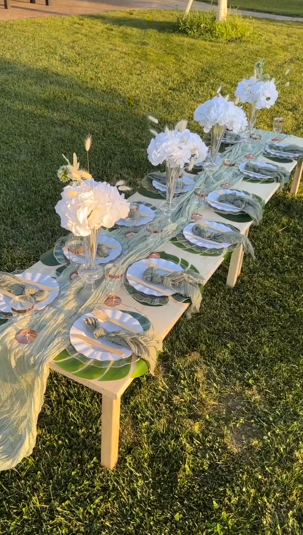 Picnic table with runners, vases, flowers, and disposable dinnerware