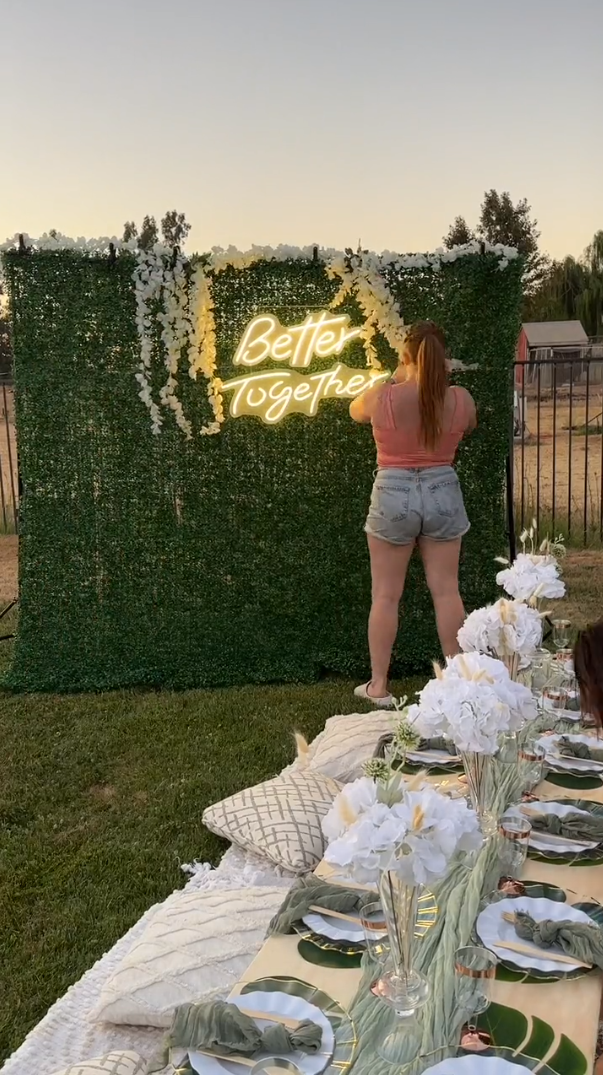 Green wall backdrop with neon light sign and hanging floral garlands