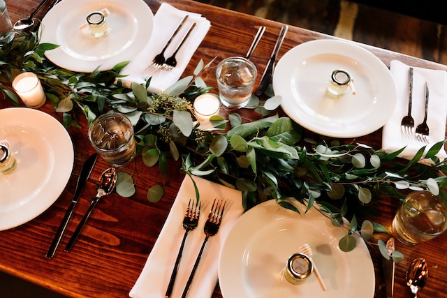 Table setting with disposable dinnerware, napkins, greenery, and candles