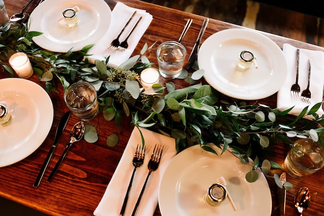 Rehearsal dinner tablescape with dinnerware and greenery centerpiece