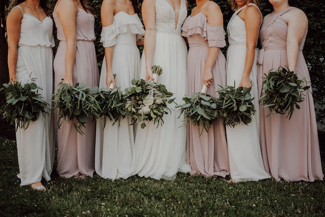 Bride and bridesmaids holding flower bouquets and greenery