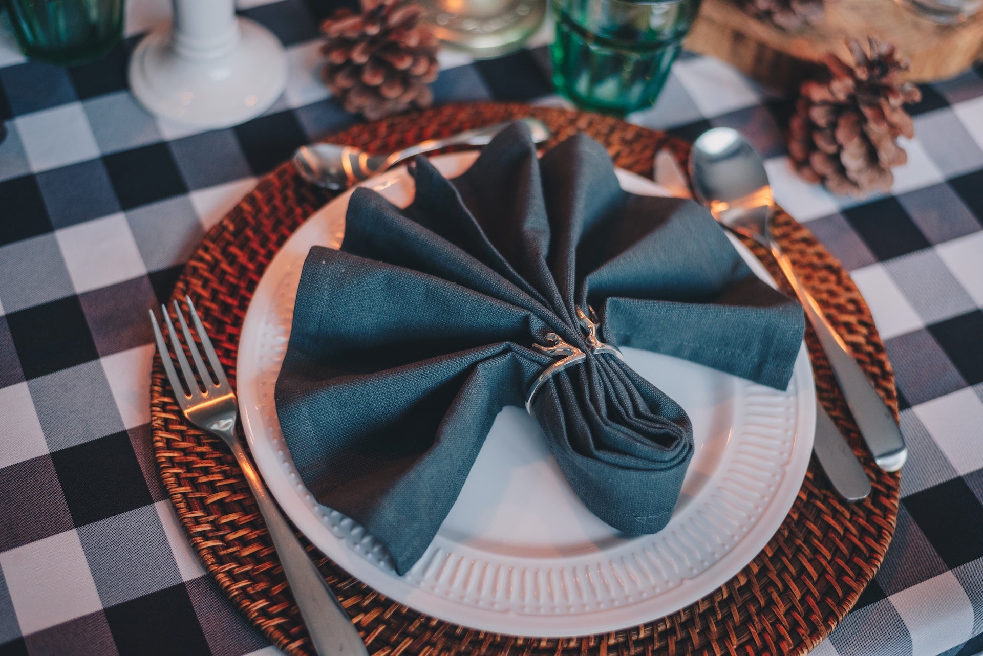 Dinner napkin tucked in a napkin ring and arranged on top of a dinner plate