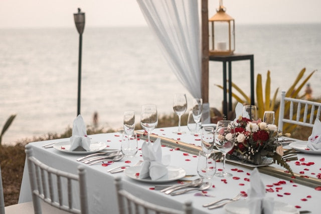 Seaside wedding tablescape with red floral centerpiece and lantern
