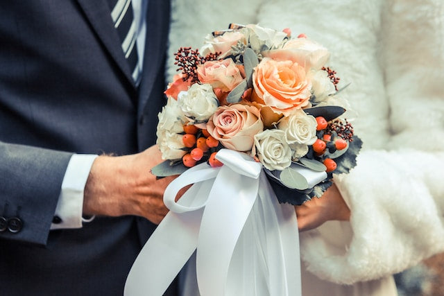 Bride and groom holding a flower bouquet with ribbons