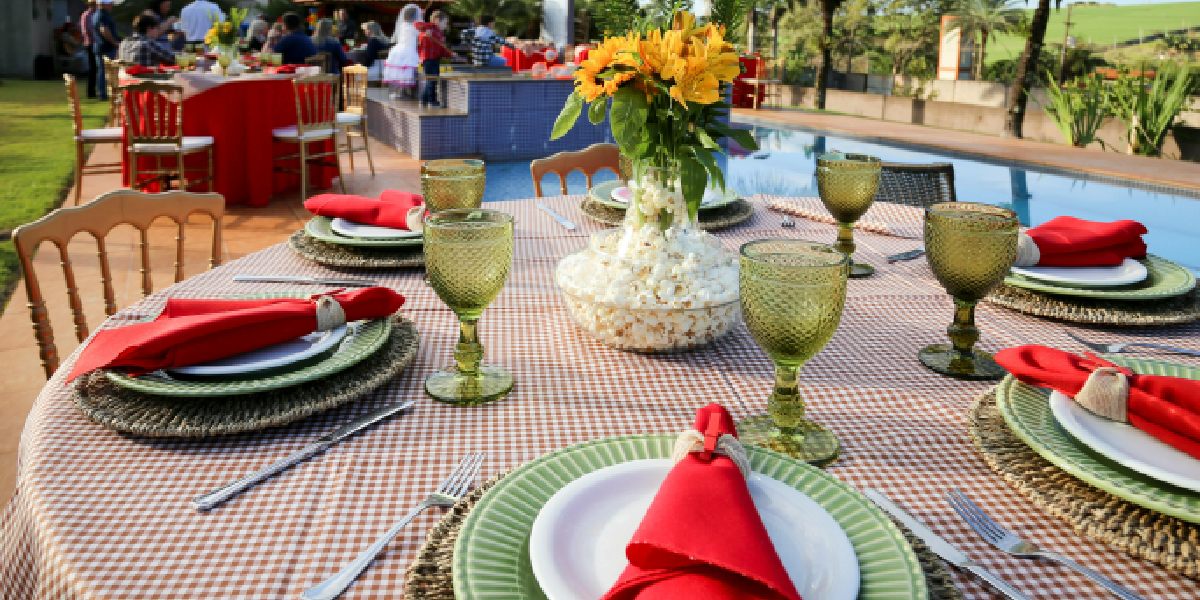 outdoor table setting with red napkins, green glasses, and a floral centerpiece