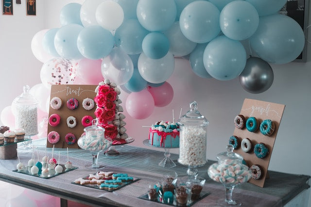 Dessert display with cake stands, donut bar, serving platters, and balloons
