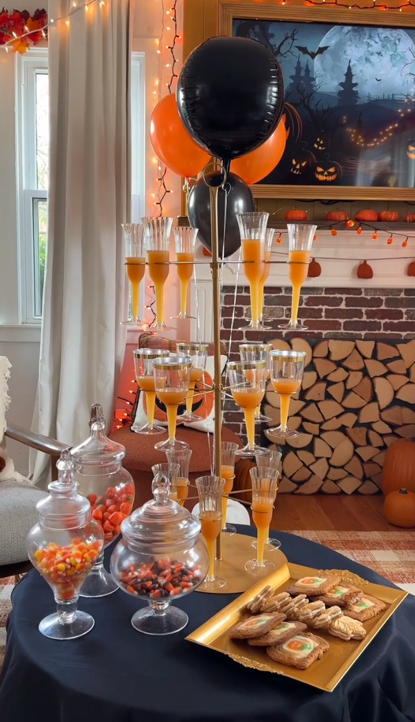 Dessert table with tablecloth, wine glass stand, serving tray, candy jars, and balloon decor