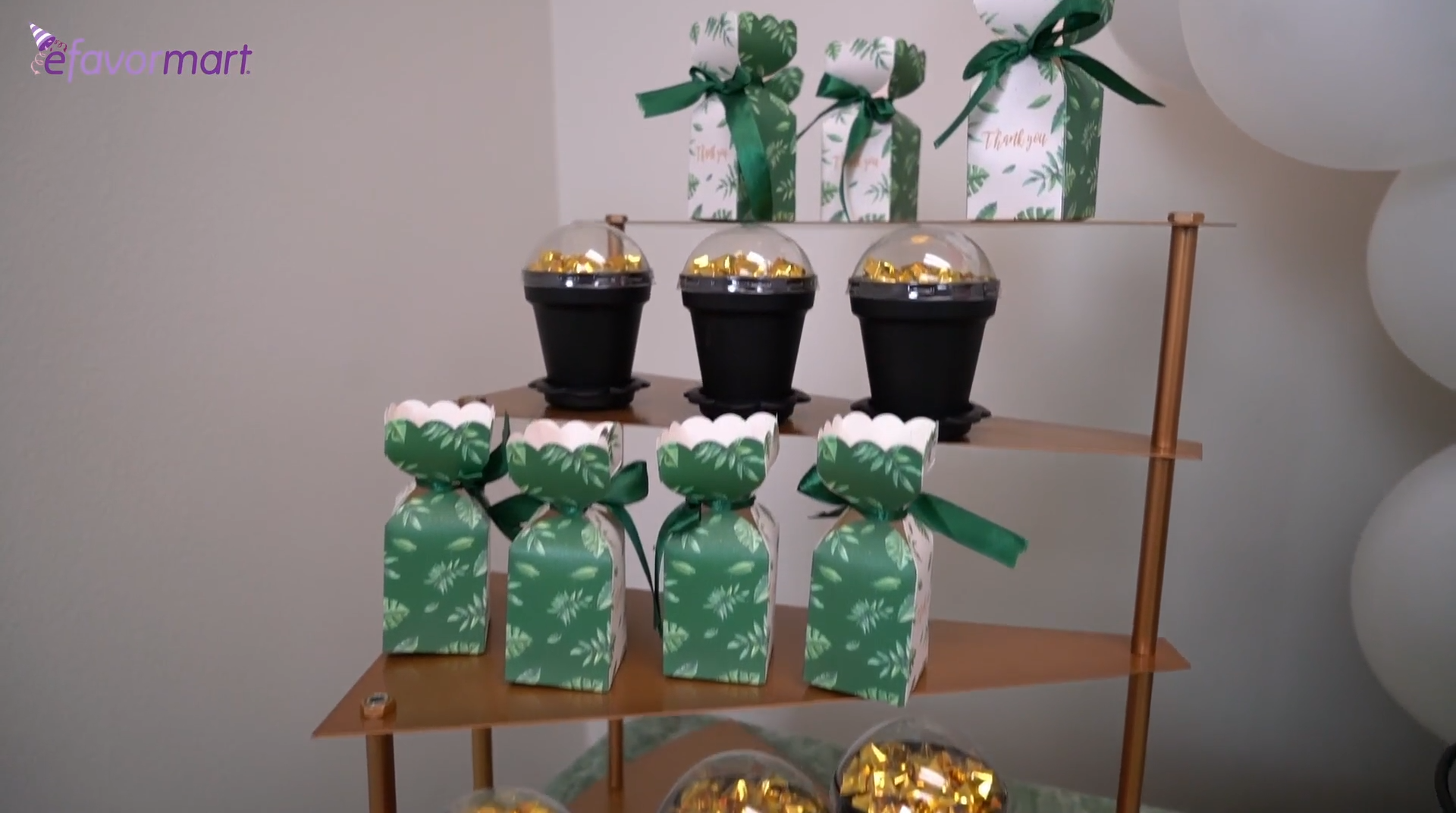 Green party favor boxes with satin ribbons and black dessert cups on a cupcake stand