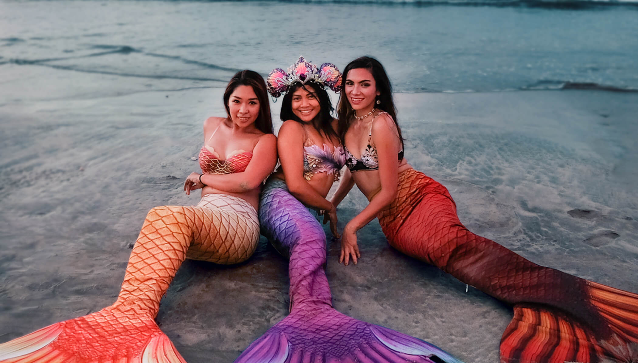 Ladies in mermaid costumes on the beach