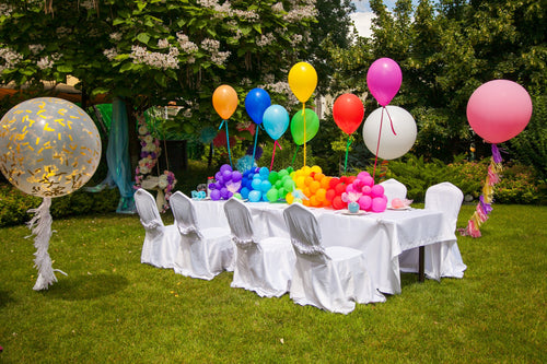 birthday party with balloons, chair covers and tablecloths