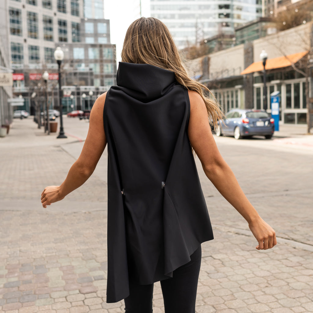A woman wearing a black sustainable asymmetrical vest by Malaika New York in ECONYL fibers regenerated nylon